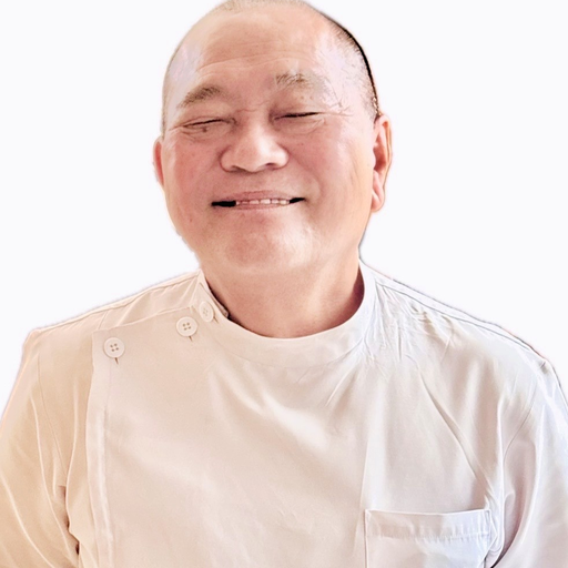 施術者 平良恵忠の写真。白衣すがたで、やわらかい笑顔の年配の男性。